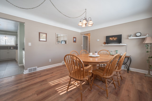 dining space featuring dark wood-type flooring, a notable chandelier, and sink