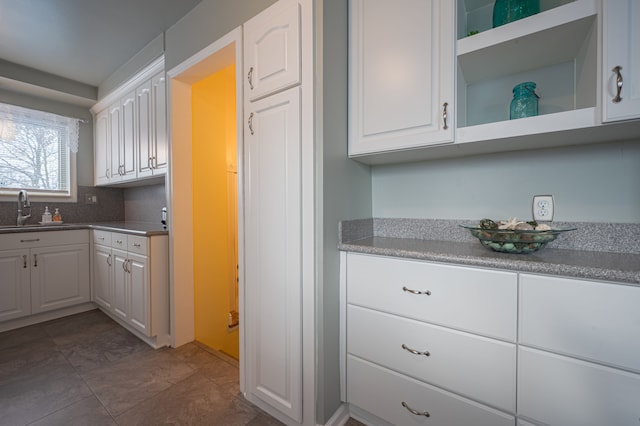 kitchen with decorative backsplash, sink, and white cabinets