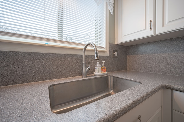 interior details featuring sink, white cabinets, and tasteful backsplash