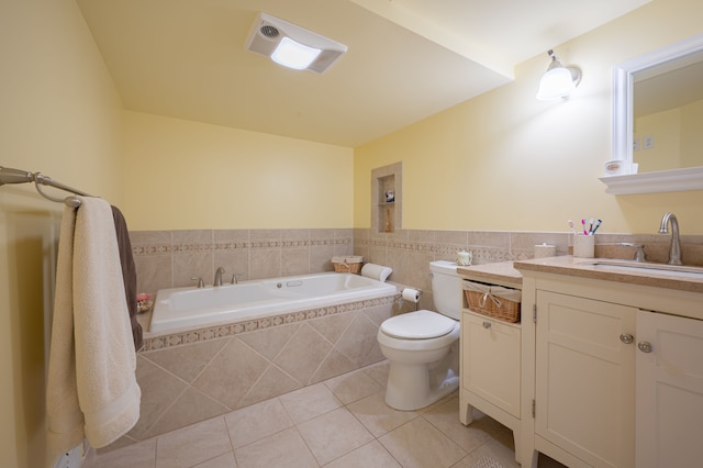 bathroom featuring tile walls, vanity, tiled tub, tile patterned flooring, and toilet