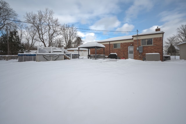 snow covered back of property featuring a deck