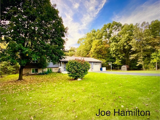 view of yard featuring aphalt driveway and a garage