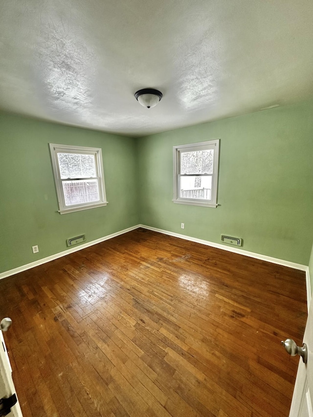 spare room with hardwood / wood-style flooring and a healthy amount of sunlight