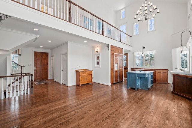 living room with a healthy amount of sunlight, dark wood-type flooring, crown molding, and a chandelier