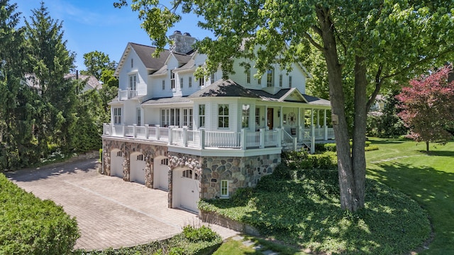 view of front of house featuring a garage, a balcony, a porch, and a front yard