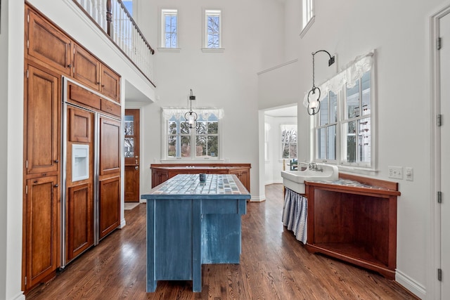 kitchen featuring dark hardwood / wood-style floors, tile countertops, hanging light fixtures, paneled built in refrigerator, and a center island