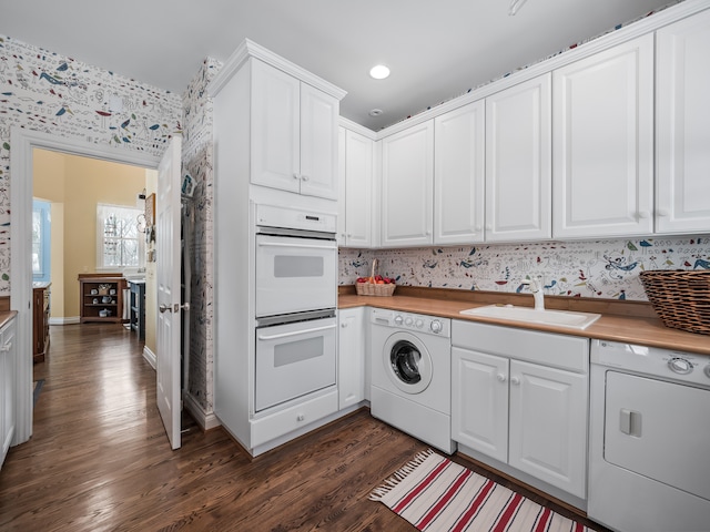 kitchen featuring washer / dryer, sink, white cabinets, and white double oven