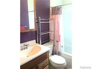 full bathroom with shower / tub combo with curtain, vanity, and toilet