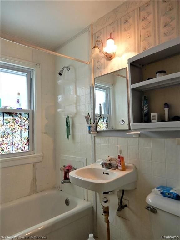 full bathroom featuring tiled shower / bath, sink, tile walls, decorative backsplash, and toilet