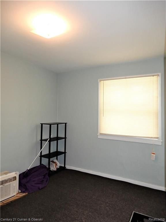 carpeted spare room featuring a wall unit AC