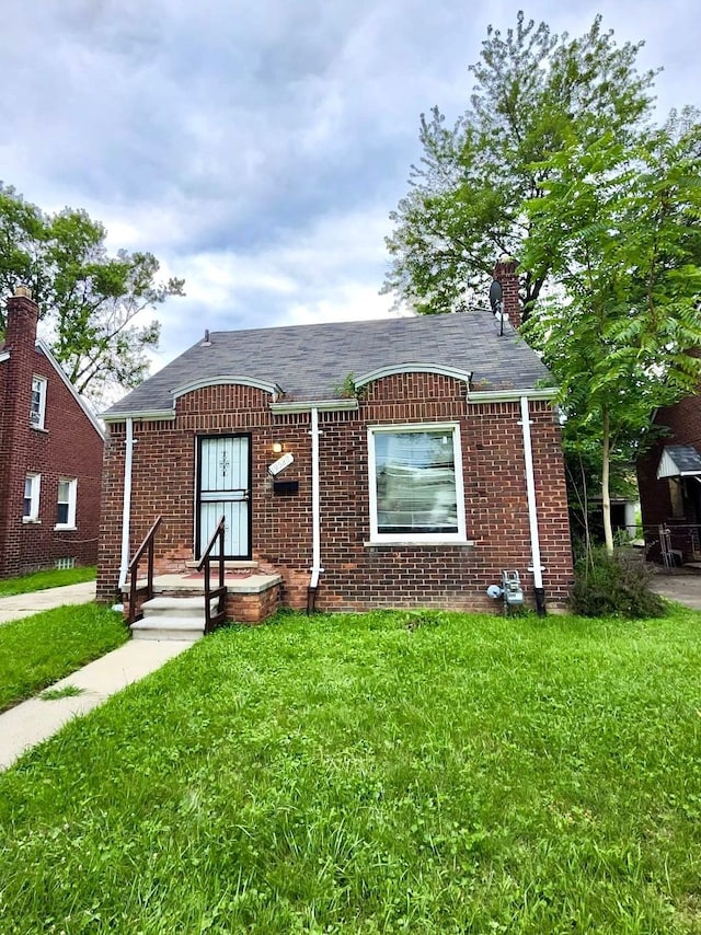 bungalow with a front yard and brick siding