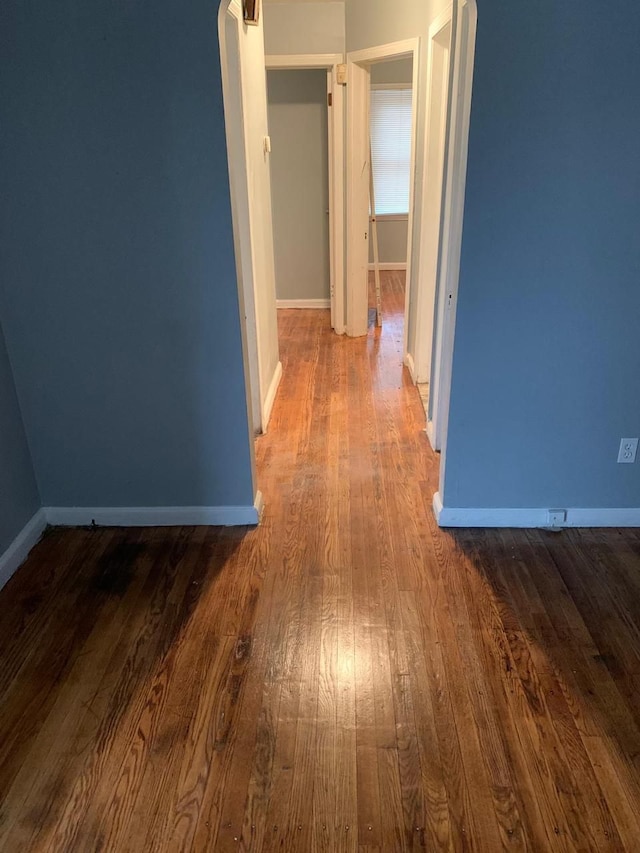 hallway with baseboards and wood finished floors