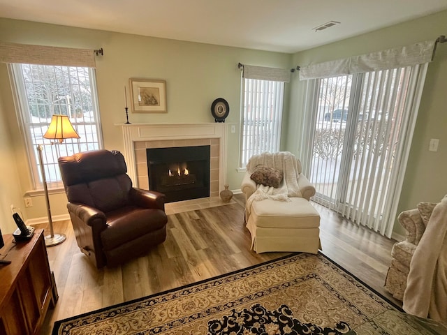 sitting room with a tile fireplace, a wealth of natural light, and light hardwood / wood-style flooring