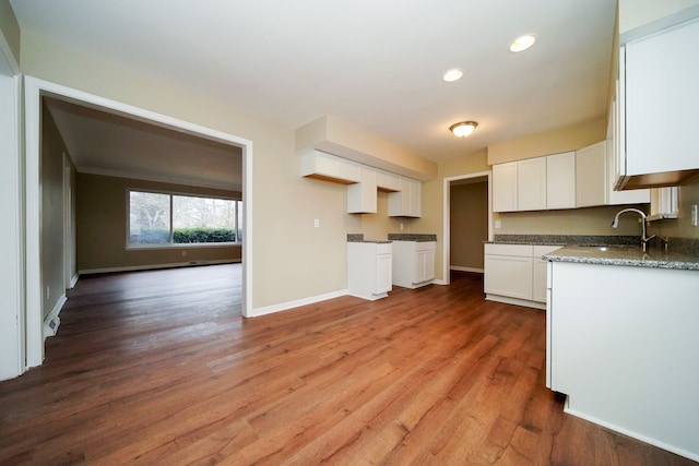 kitchen with hardwood / wood-style flooring, stone countertops, sink, and white cabinets