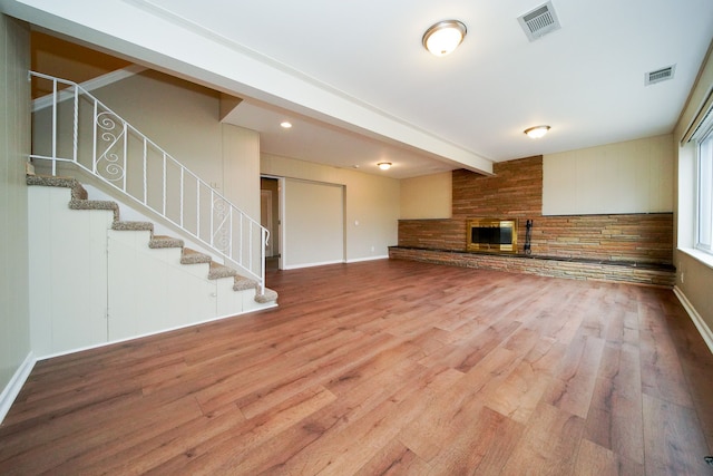 unfurnished living room featuring a fireplace, hardwood / wood-style floors, and beam ceiling