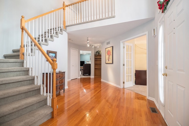 foyer entrance featuring hardwood / wood-style flooring and a towering ceiling