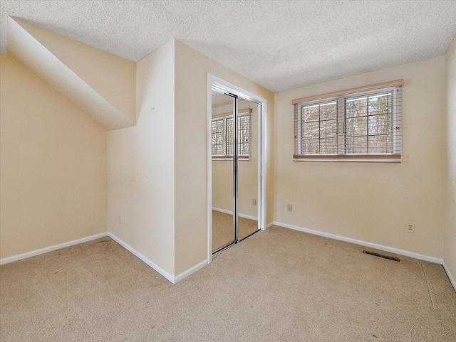 unfurnished bedroom with a closet, light carpet, and a textured ceiling