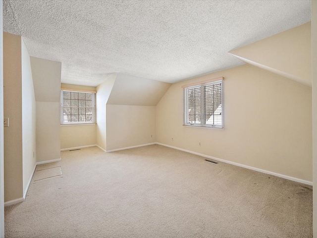 bonus room featuring a textured ceiling, lofted ceiling, and carpet floors