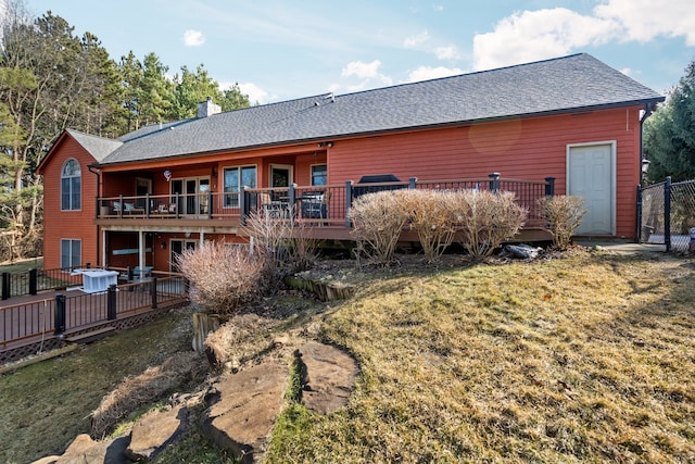 rear view of property with a wooden deck, roof with shingles, and a chimney