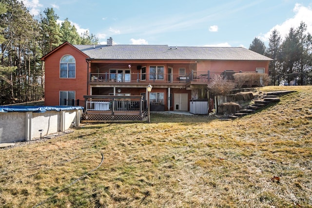 rear view of house with a covered pool, a yard, a chimney, and a deck