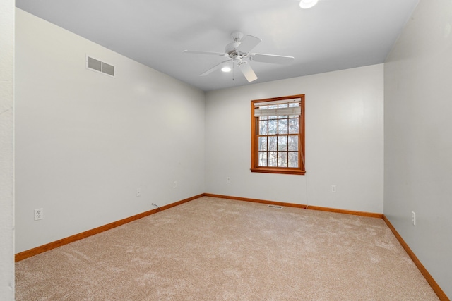 empty room featuring visible vents, light colored carpet, baseboards, and ceiling fan