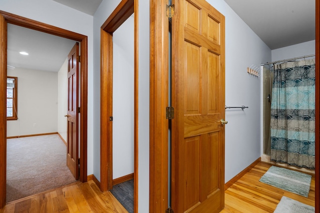 hall with light wood-type flooring and baseboards