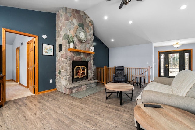 living area featuring a ceiling fan, wood finished floors, a fireplace, baseboards, and vaulted ceiling