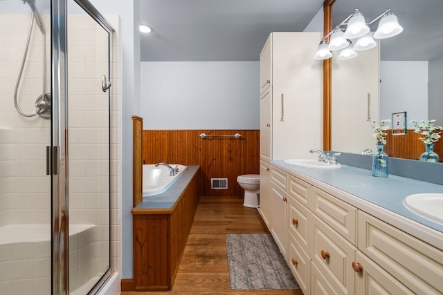 full bathroom with visible vents, a wainscoted wall, a stall shower, wood finished floors, and a sink