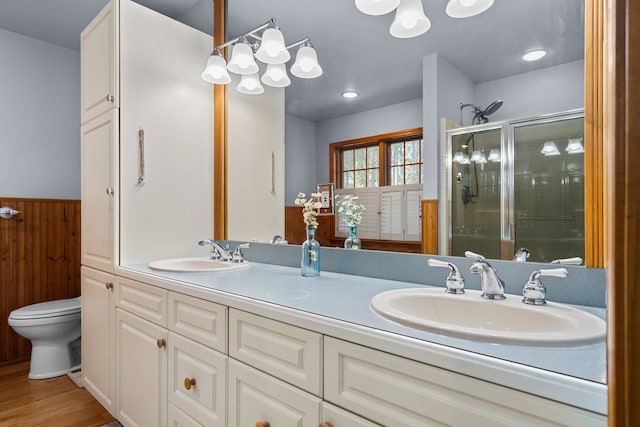 bathroom featuring a sink, wood finished floors, toilet, and a stall shower