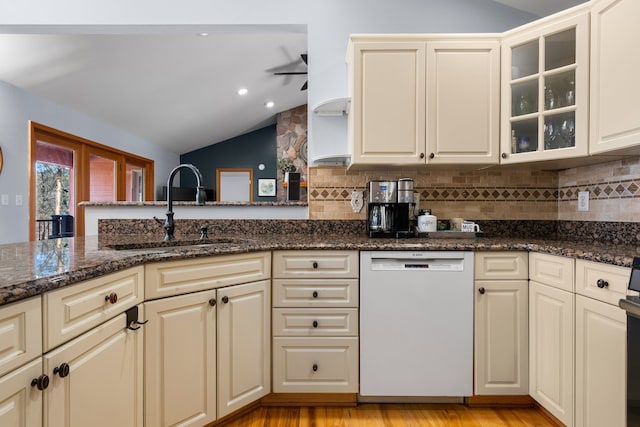 kitchen featuring light wood finished floors, tasteful backsplash, lofted ceiling, white dishwasher, and a sink