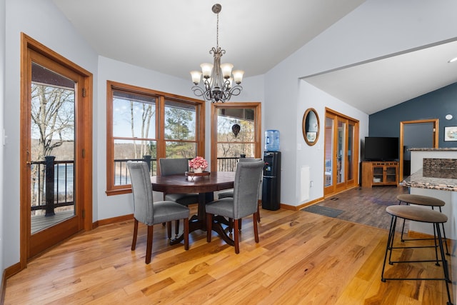 dining space with an inviting chandelier, lofted ceiling, light wood-style floors, and baseboards