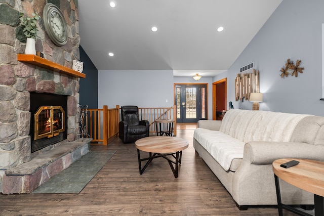 living area featuring visible vents, lofted ceiling, a stone fireplace, french doors, and wood finished floors