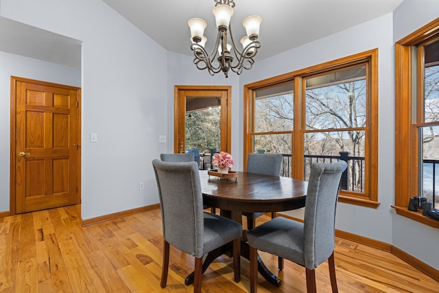 dining area with baseboards, an inviting chandelier, and light wood finished floors