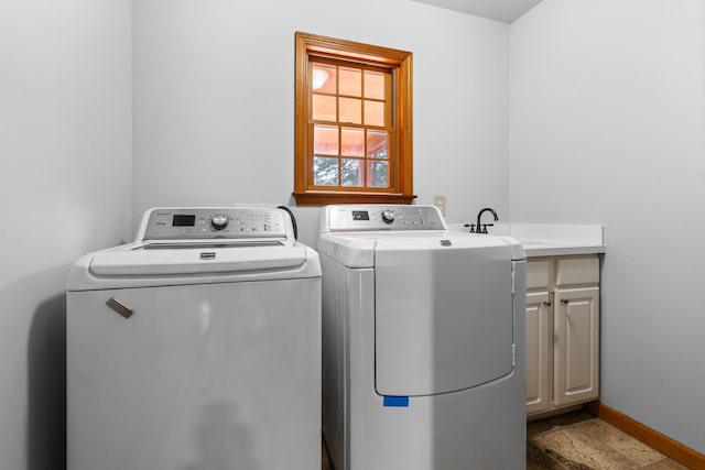 clothes washing area with a sink, cabinet space, baseboards, and separate washer and dryer