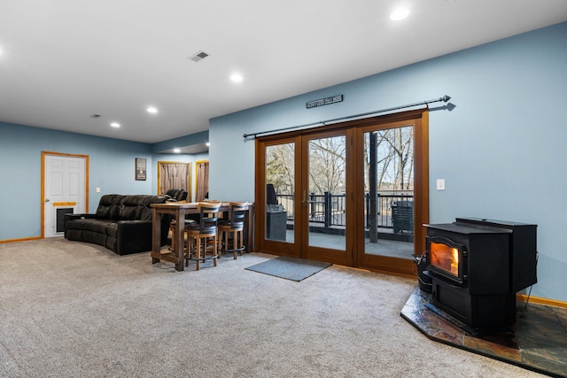 carpeted living room featuring visible vents, recessed lighting, french doors, baseboards, and a wood stove