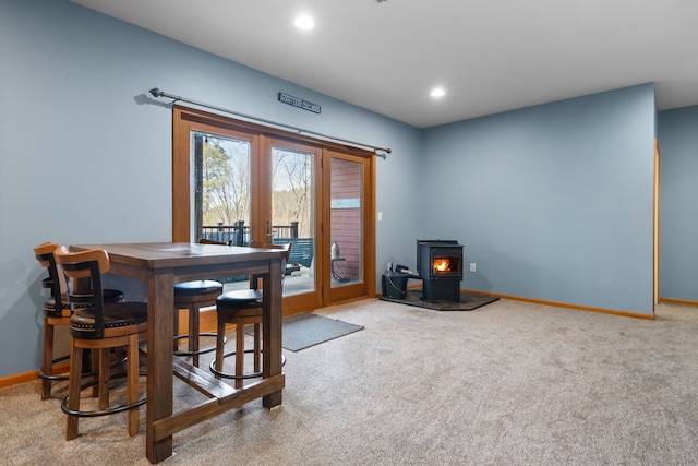 carpeted dining space featuring recessed lighting, french doors, baseboards, and a wood stove