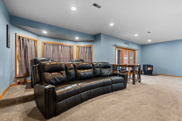 living room featuring visible vents, baseboards, carpet floors, recessed lighting, and a wood stove