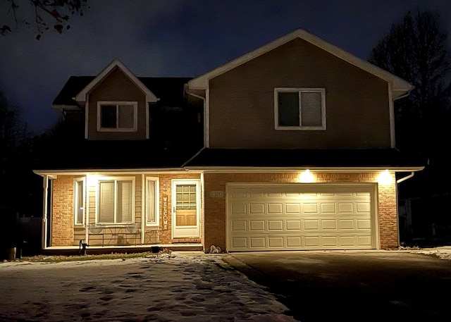 view of front of home with aphalt driveway, covered porch, brick siding, and a garage