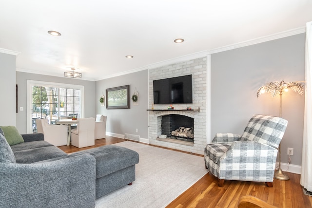 living room with a fireplace, baseboards, crown molding, and wood finished floors