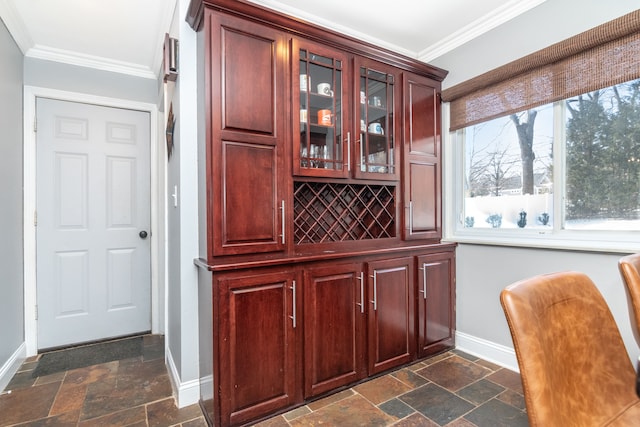 bar with baseboards, ornamental molding, and stone tile flooring