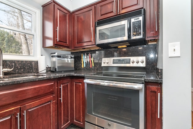 kitchen with stainless steel electric range oven, tasteful backsplash, a sink, and reddish brown cabinets