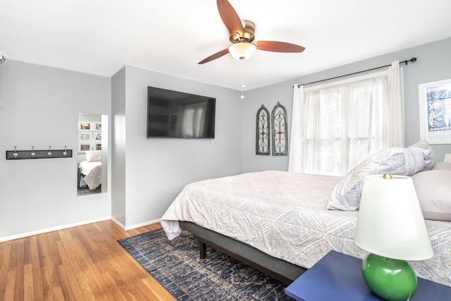 bedroom with wood finished floors, a ceiling fan, and baseboards