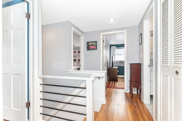 hall with light wood-style flooring and an upstairs landing