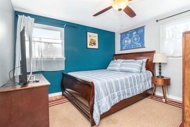 bedroom with light wood-style flooring, baseboards, and ceiling fan