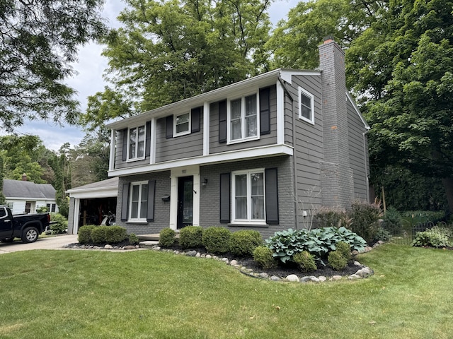 colonial-style house with an attached garage, brick siding, concrete driveway, a chimney, and a front yard