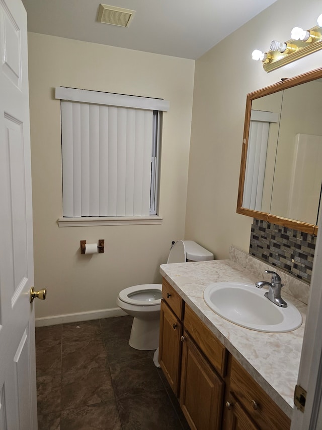 bathroom with vanity, tasteful backsplash, and toilet