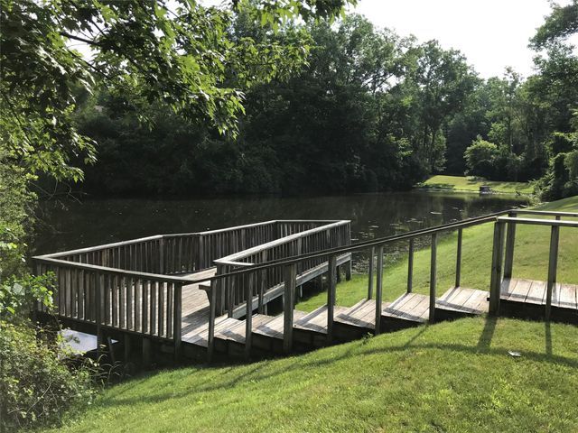 dock area featuring a lawn and a deck with water view