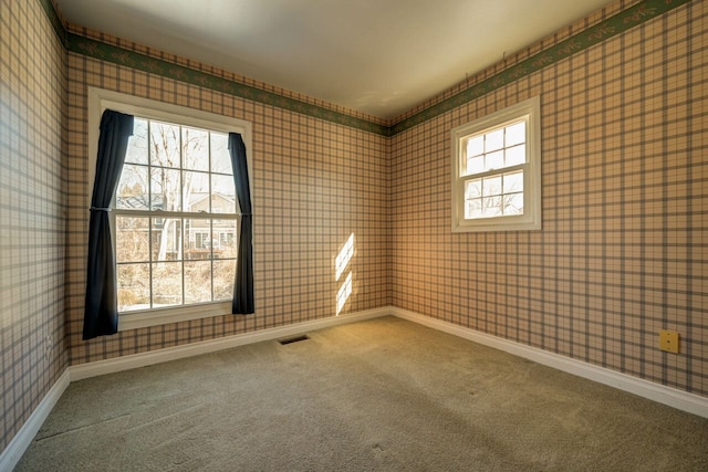 carpeted spare room with wallpapered walls, baseboards, and visible vents