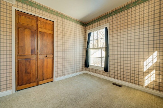 unfurnished room with wallpapered walls, carpet flooring, baseboards, and visible vents