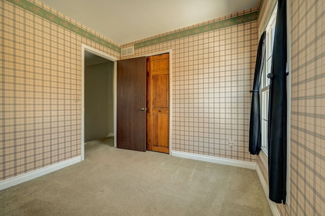 carpeted spare room with visible vents, baseboards, and wallpapered walls